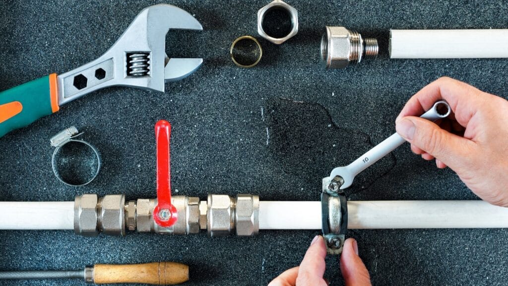 Plumber repairing a pipe valve with an adjustable wrench in Denver