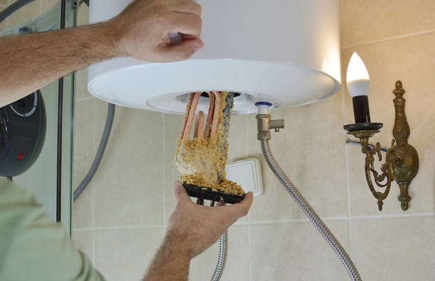 Technician removing mineral buildup from a water heater in Denver