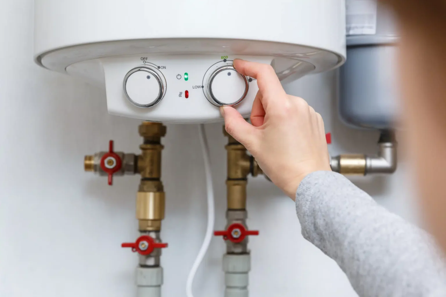 Homeowner adjusting the temperature controls on a water heater in Denver
